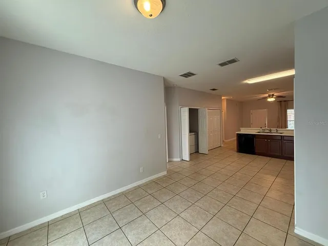 a view of an empty room and chandelier fan