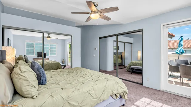 a bedroom with a large bed and a chandelier fan