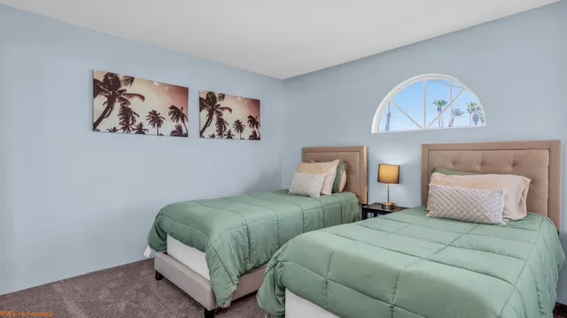 a bedroom with two beds and a painting on the wall