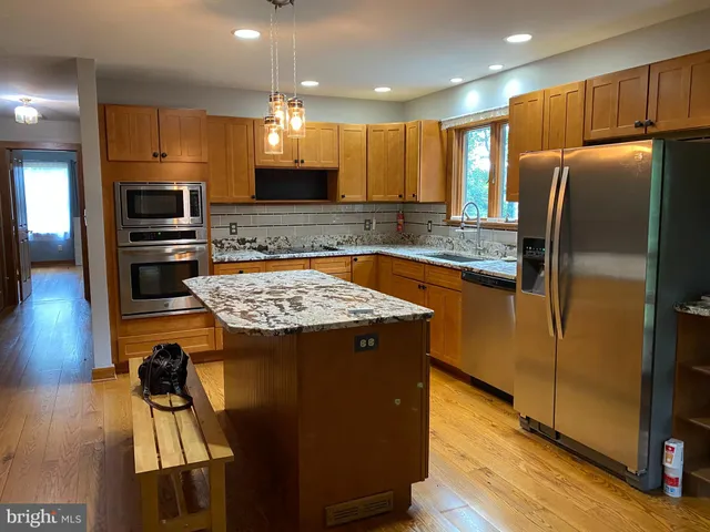a kitchen with kitchen island granite countertop wooden cabinets and a refrigerator