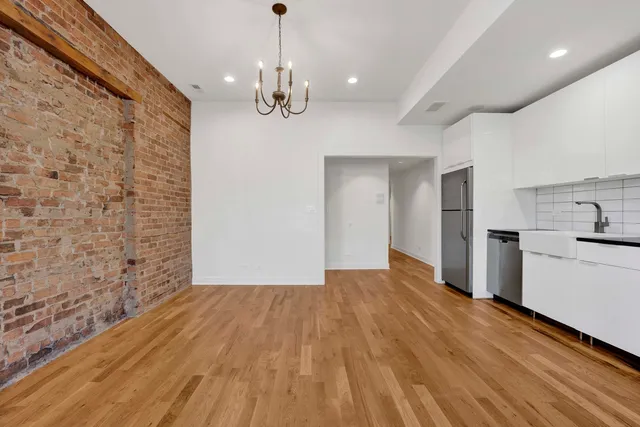 a view of empty room with wooden floor and kitchen view
