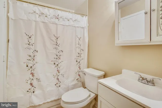 a white toilet sitting next to a white sink and a shower curtain