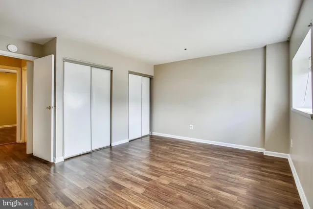 a view of an empty room with wooden floor and closet