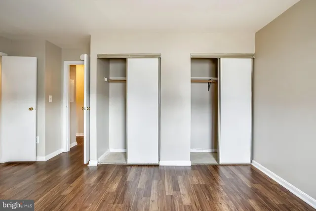 a view of an empty room with closet and wooden floor