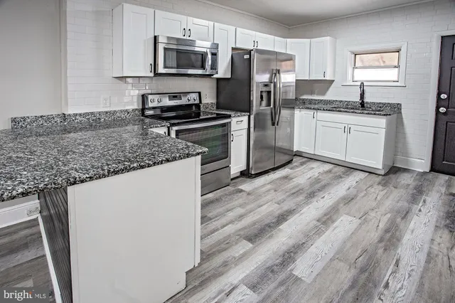 a kitchen with granite countertop a sink stainless steel appliances and cabinets