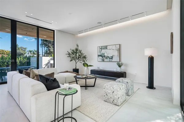 a living room with furniture large windows and wooden floor