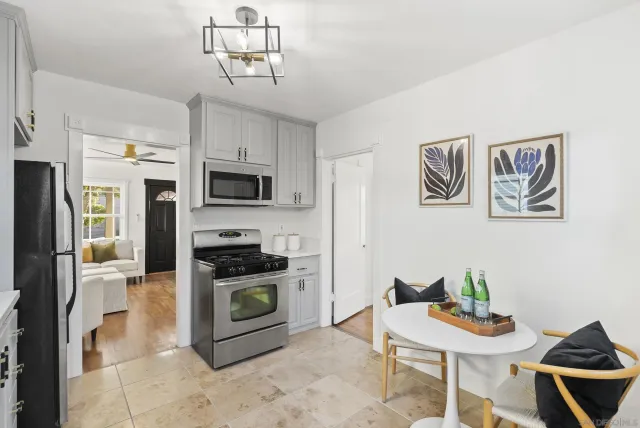 a kitchen with stainless steel appliances granite countertop a stove a microwave a dining table and chairs with wooden floor