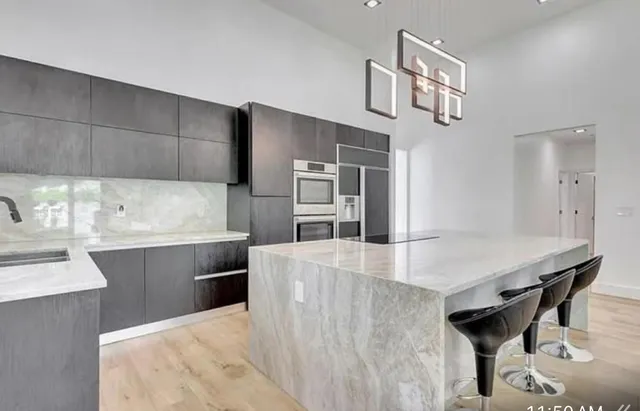 a kitchen with kitchen island a counter top space a sink stainless steel appliances and cabinets