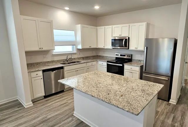 a kitchen with stainless steel appliances granite countertop a sink stove microwave and refrigerator