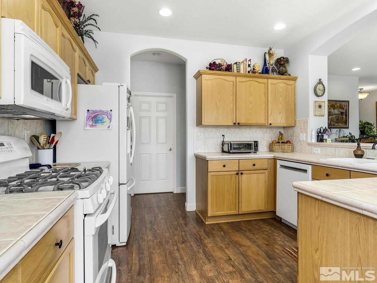 10150 Robilee Court Reno, NV 89521 - Photo 7 of 40 a kitchen with stainless steel appliances granite countertop a stove a sink dishwasher and a refrigerator with wooden floor