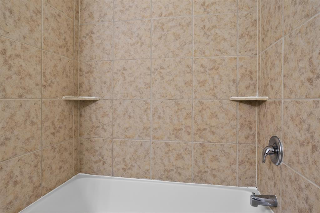 8728 Maple Ridge Trail Fort Worth, TX 76244 - Photo 28 of 40 Bathtub with light-toned tiled surround, featuring two corner shelves and chrome fixtures