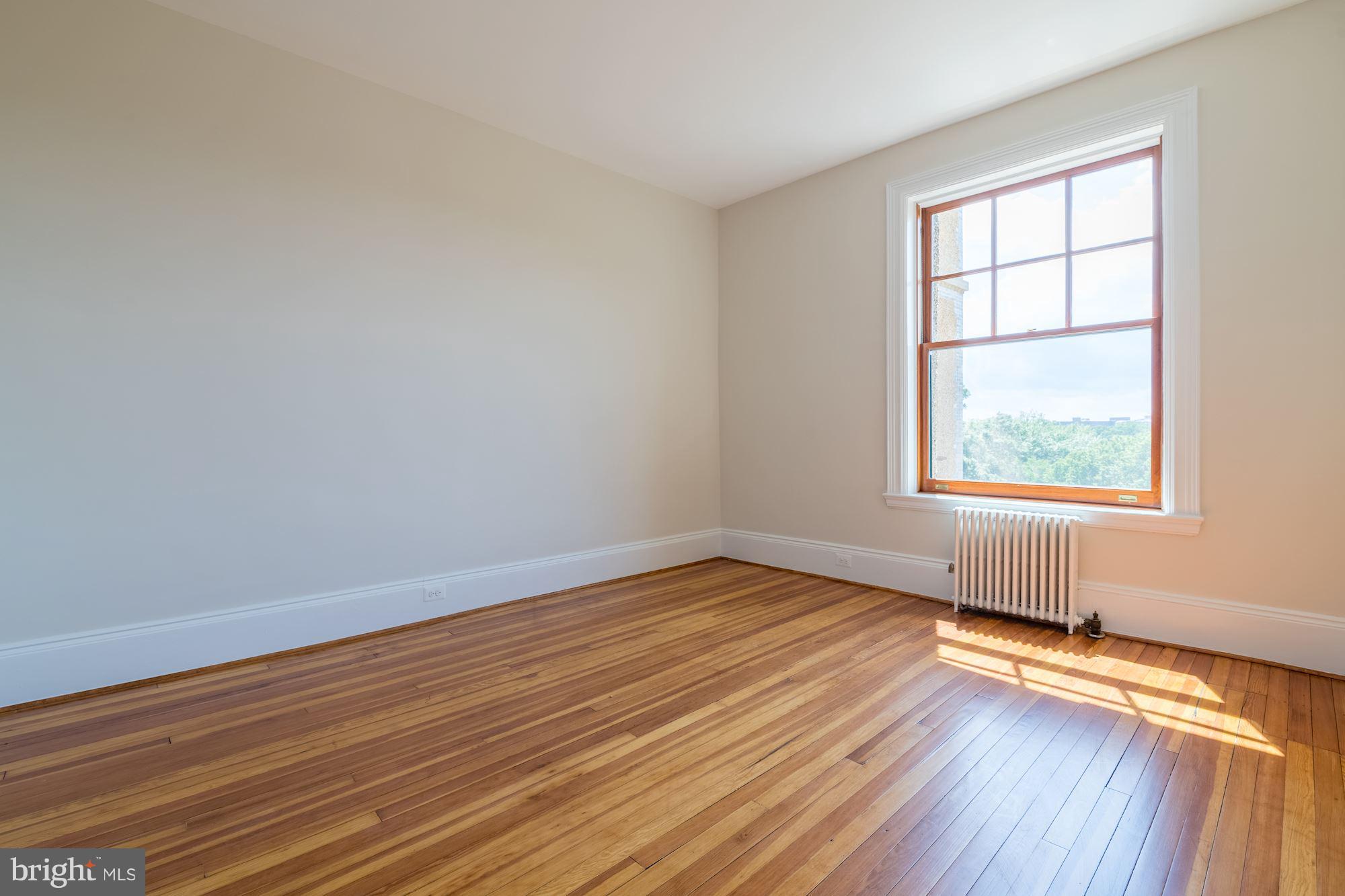 2853 Ontario Road Northwest, Unit 505 Washington, DC 20009 - Photo 19 of 29 an empty room with wooden floor and windows