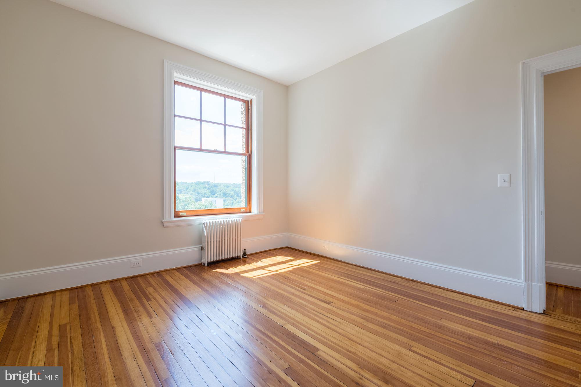2853 Ontario Road Northwest, Unit 505 Washington, DC 20009 - Photo 20 of 29 an empty room with wooden floor and windows