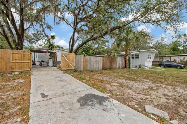 a view of a white house with a large tree and wooden fence