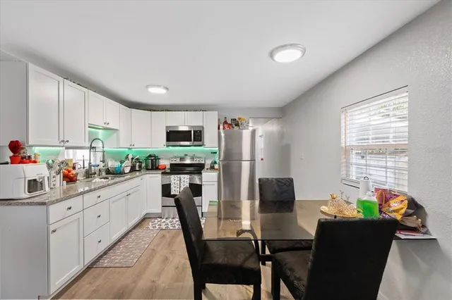 a kitchen with stainless steel appliances a dining table chairs a refrigerator a stove a microwave and dining table