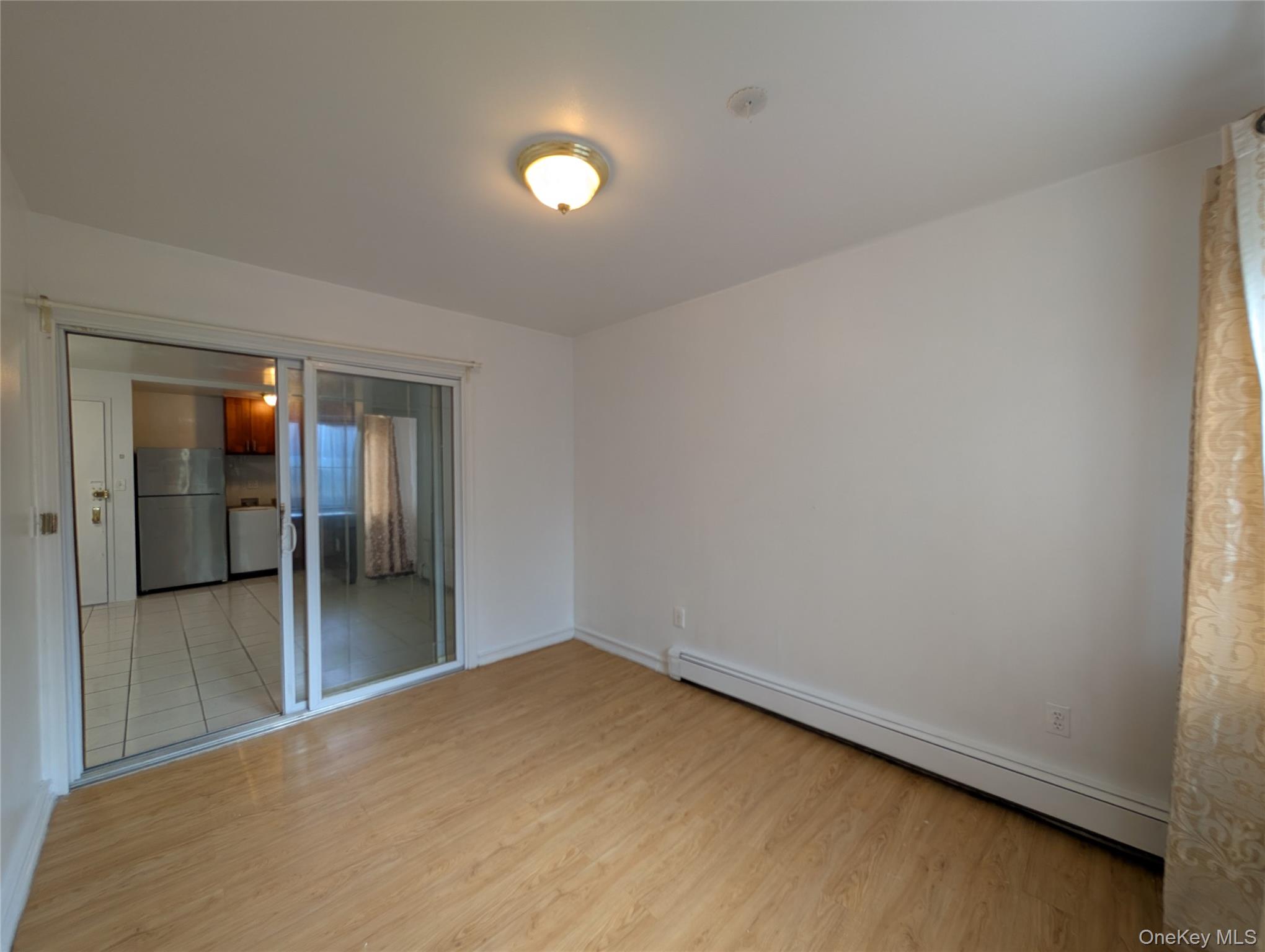 43-04 158th Street, Unit L4 Queens, NY 11358 - Photo 14 of 21 Unfurnished room with baseboard heating and light wood-style flooring