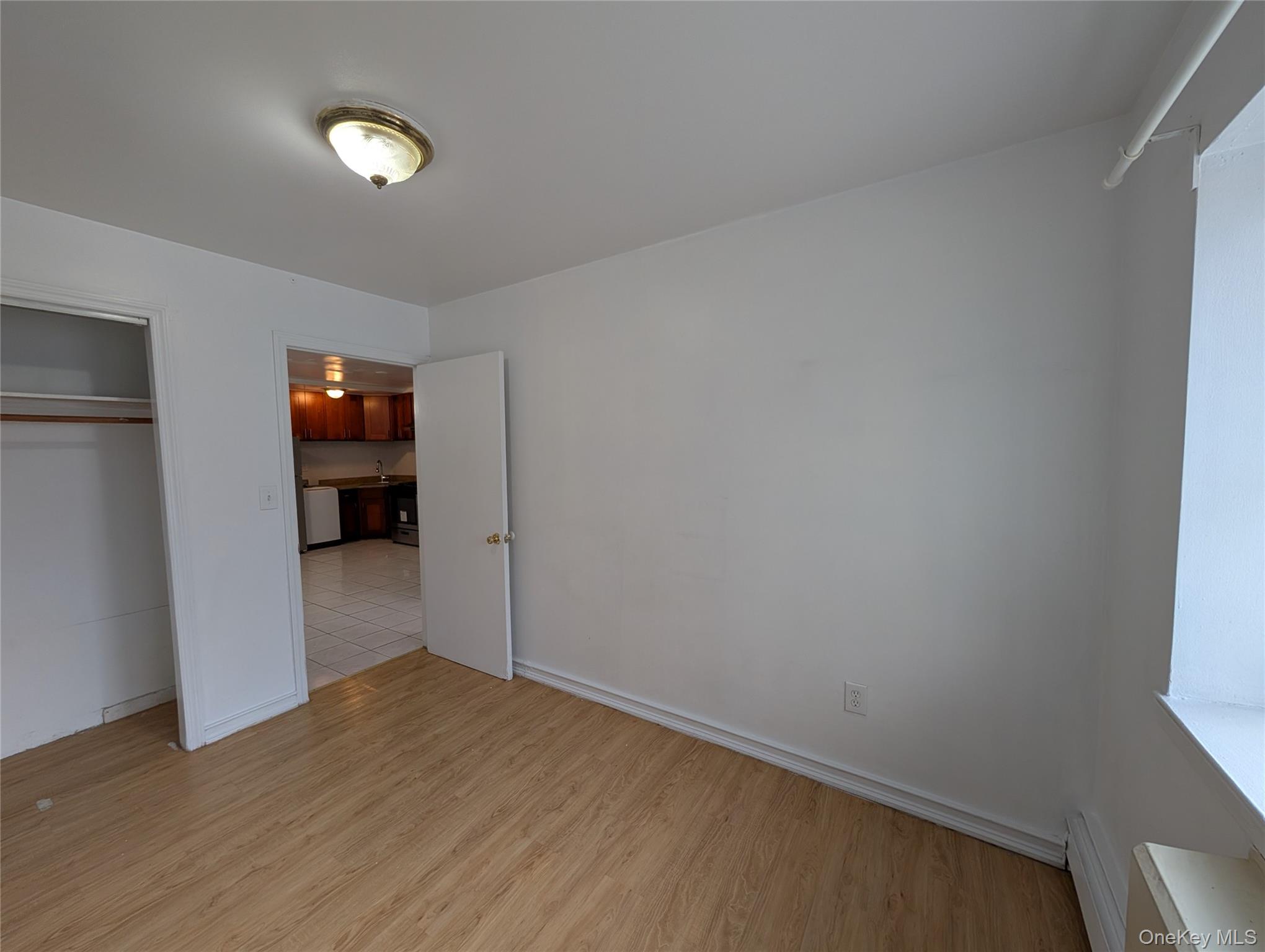 43-04 158th Street, Unit L4 Queens, NY 11358 - Photo 18 of 21 Unfurnished bedroom featuring light wood-style flooring, baseboard heating, and a closet