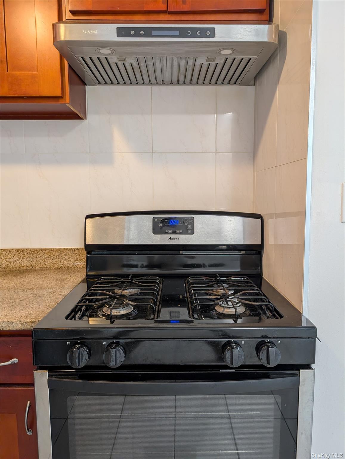 43-04 158th Street, Unit L4 Queens, NY 11358 - Photo 4 of 21 Kitchen with black gas stove, ventilation hood, decorative backsplash, and brown cabinets