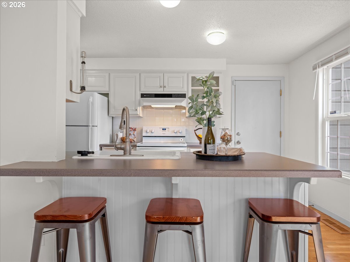 3775 3rd Avenue North Keizer, OR 97303 - Photo 14 of 32 a kitchen with stainless steel appliances granite countertop a table chairs in it white cabinets and a window