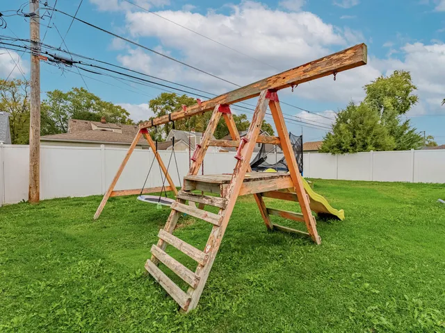 a view of a backyard with a slide and a wooden fence