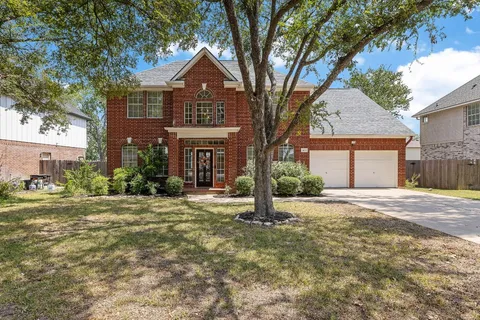 a front view of a house with a garden and trees