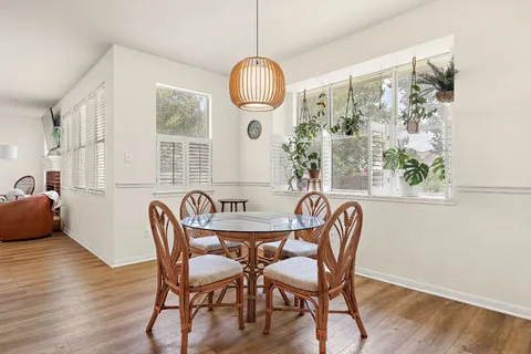 a dining room with wooden floor a chandelier a glass table and chairs
