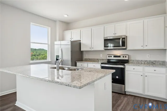 a kitchen with granite countertop a sink stainless steel appliances and white cabinets