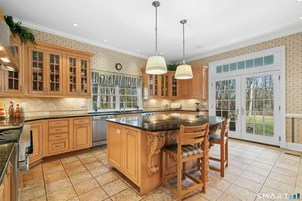 a dining hall with stainless steel appliances granite countertop a stove a kitchen island a dining table and chairs