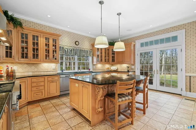 a dining hall with stainless steel appliances granite countertop a stove a kitchen island a dining table and chairs