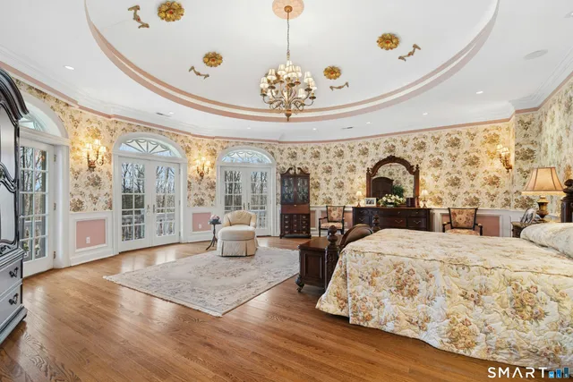 a large bedroom with wooden floor and large windows