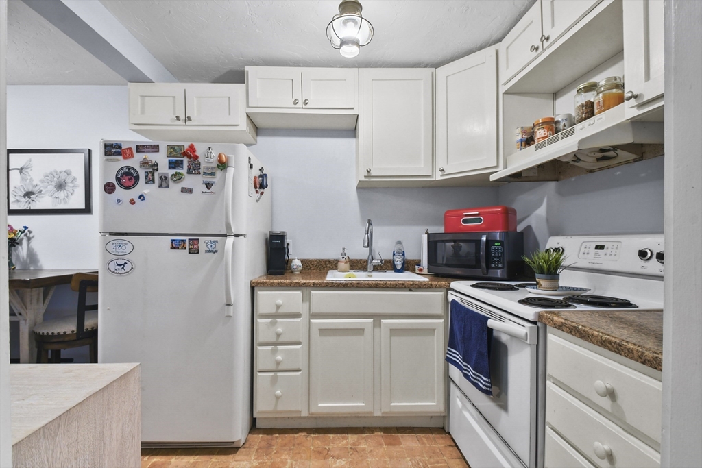 976 Plain Street, Unit 48 Marshfield, MA 02050 - Photo 5 of 20 a kitchen with stainless steel appliances granite countertop a refrigerator sink stove and white cabinets