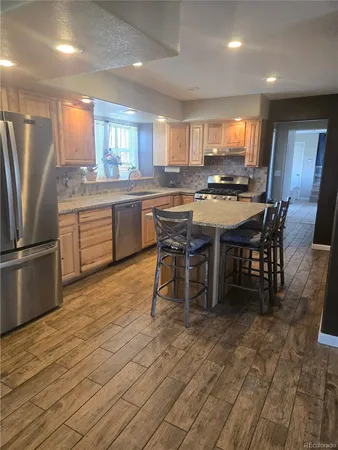 a kitchen with stainless steel appliances kitchen island granite countertop a table chairs sink and cabinets
