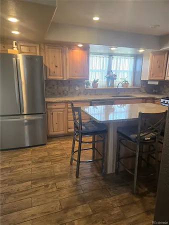 a kitchen with kitchen island a dining table chairs refrigerator and cabinets