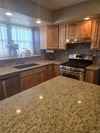 a kitchen with stainless steel appliances granite countertop a stove a sink and a microwave