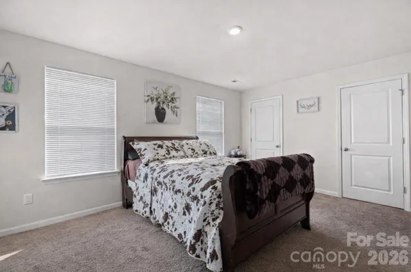 a bed sitting in a bedroom next to a window and a wooden floor