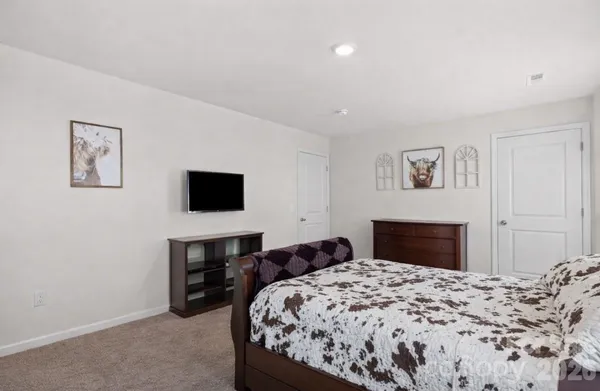 a bed sitting in a bedroom and a flat screen tv