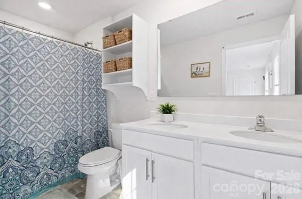 a bathroom with a granite countertop toilet sink and mirror