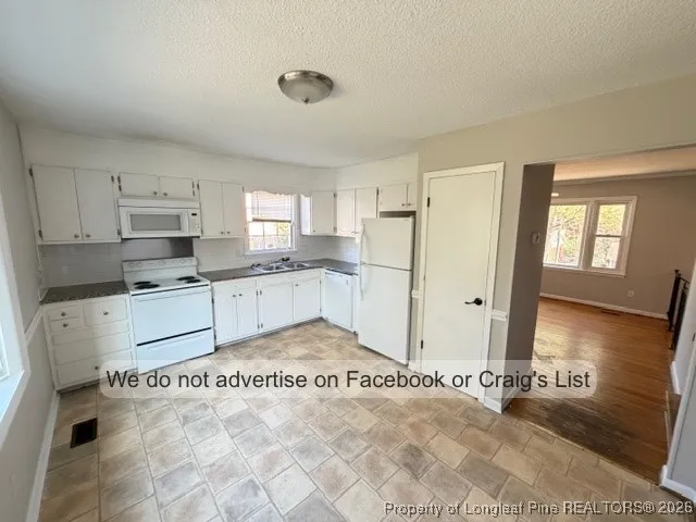 a kitchen with granite countertop a refrigerator and white cabinets