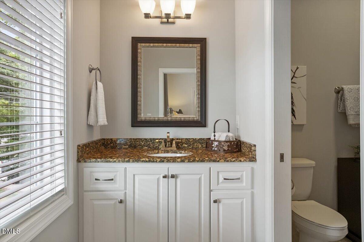1404 Ivy Lane Raleigh, NC 27609 - Photo 22 of 37 White vanity with shaker-style cabinetry, a built-in sink, and a speckled countertop