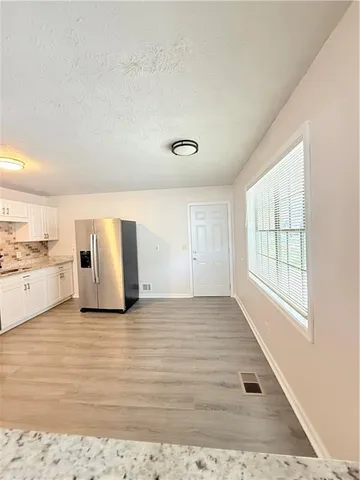 a view of a livingroom with wooden floor and kitchen