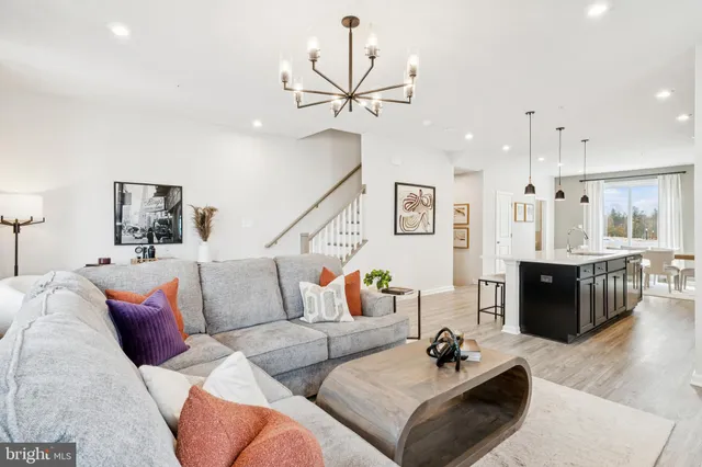 a living room with furniture kitchen view and a wooden floor