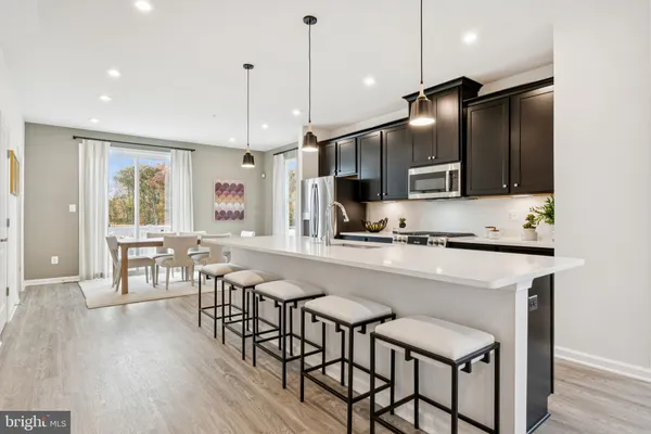 a kitchen with stainless steel appliances granite countertop a stove a refrigerator a kitchen island a dining table and chairs with wooden floor