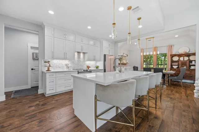 a kitchen with kitchen island granite countertop wooden floors and white cabinets