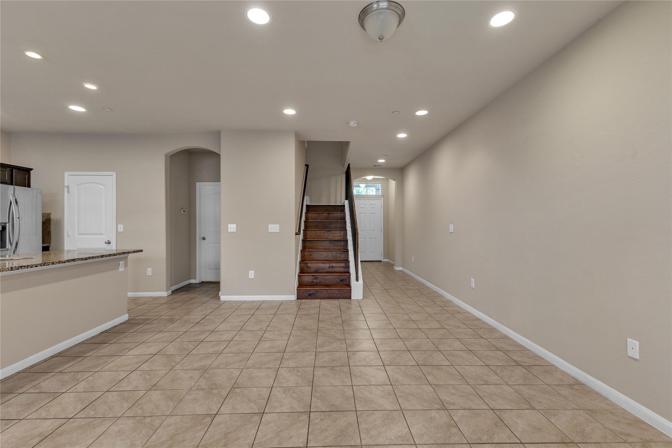 2880 Donnell Drive, Unit 2003 Round Rock, TX 78664 - Photo 7 of 31 Open-concept living space with large format tile flooring, recessed ceiling lighting, and a prominent staircase with wood-finish treads and risers