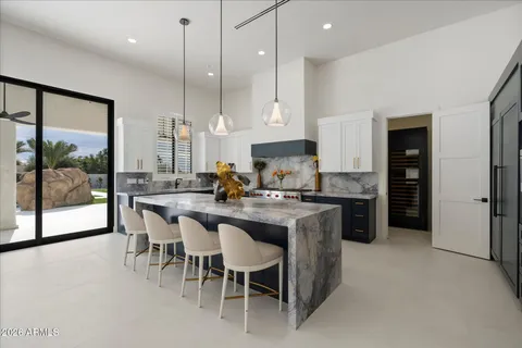 a kitchen with stainless steel appliances granite countertop a stove a sink a microwave a center island and chairs