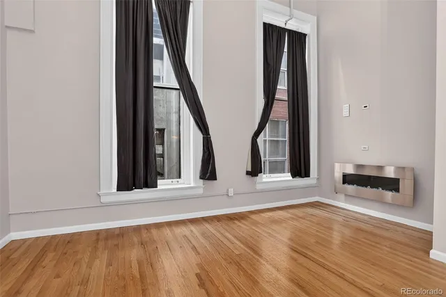 a view of an empty room with wooden floor and a window