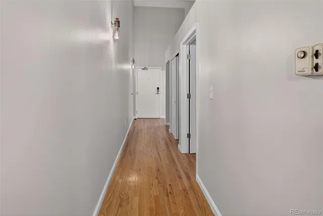 a view of a hallway with wooden floor and a bathroom