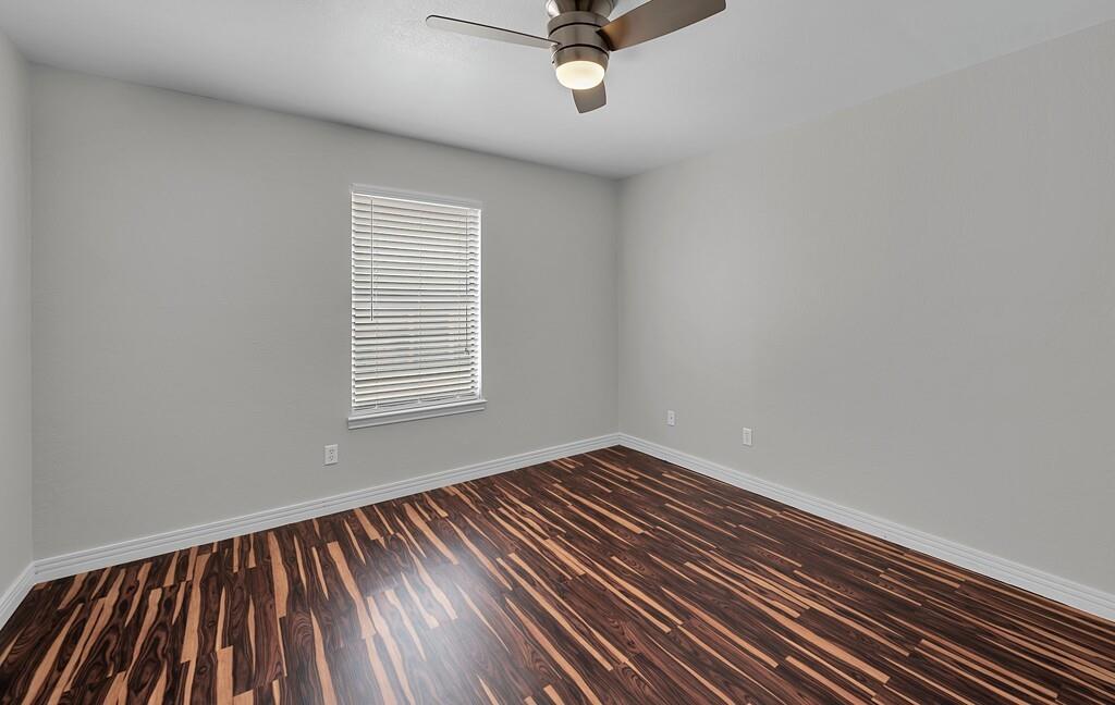 1362 South 12th Street, Unit 22 Waco, TX 76706 - Photo 18 of 31 Wood-finish flooring, light gray wall paint, window with blinds, and ceiling fan with integrated lighting