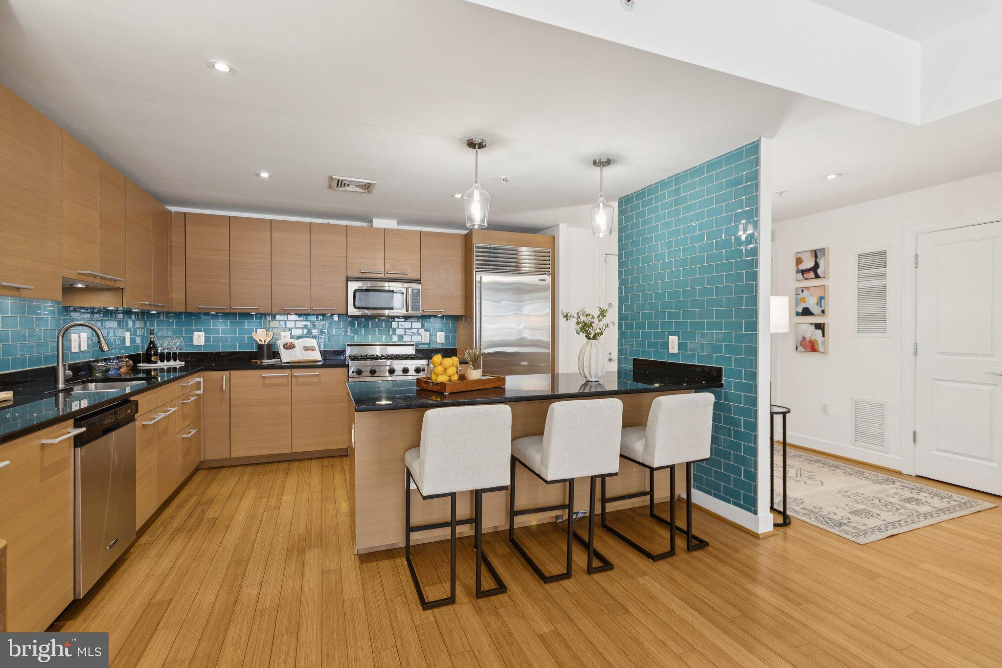 2425 L Street Northwest, Unit 210 Washington, DC 20037 - Photo 12 of 39 a kitchen with stainless steel appliances granite countertop a stove top oven a sink dishwasher a dining table and chairs with wooden floor