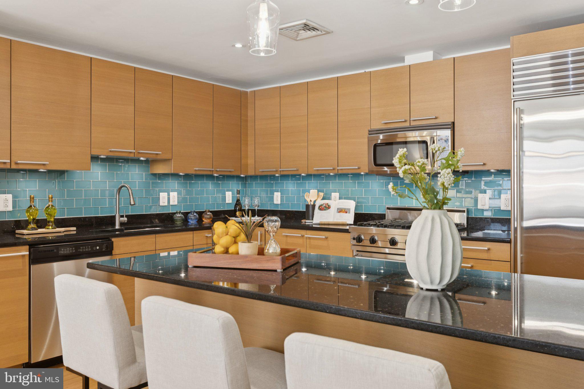 2425 L Street Northwest, Unit 210 Washington, DC 20037 - Photo 14 of 39 a kitchen with stainless steel appliances granite countertop a table chairs and a refrigerator